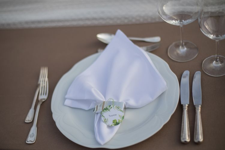 Gedeckter Tisch mit brauner Tischdecke, Spitzentischdecke und Platzkarte im Greenerystyle