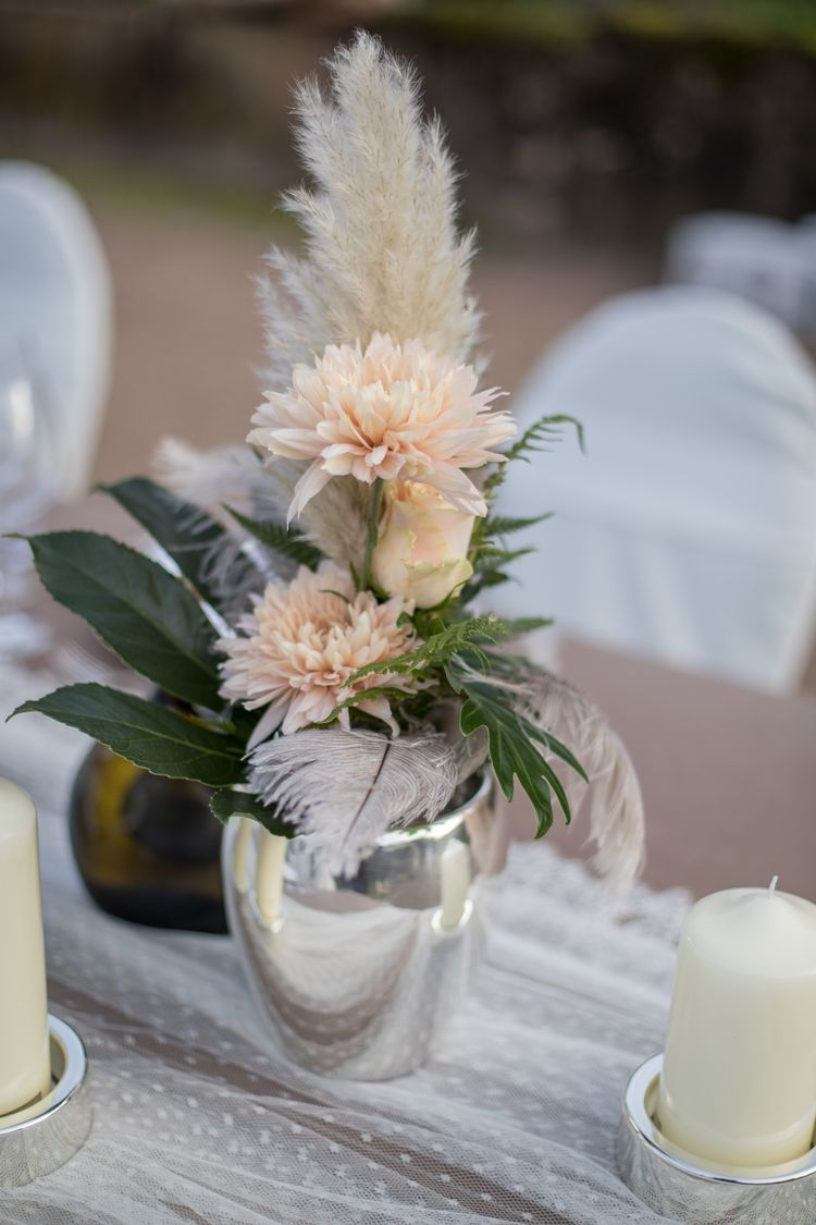 Silberne Vase mit apricot farbenen Blumen, Federn und Blattgrün
