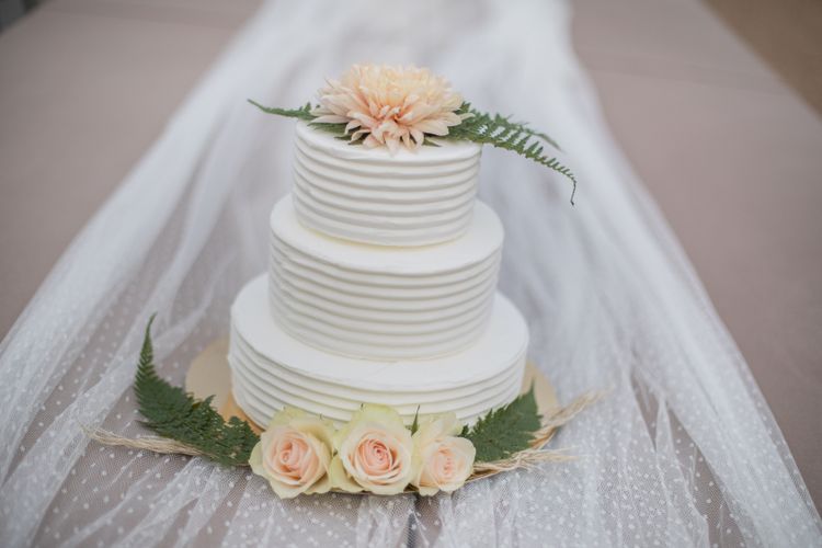 Hochzeitstorte mit Blattgrün und Apricotfarbenen Blumen dekoriert